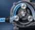 Close-up of a clear-casing rotary pump with three metal rollers and blue liquid-filled tubing looping through the mechanism