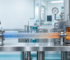 Industrial stainless steel processing line with gauges and a heated flexible coil tube transferring orange-hot liquid to a reactor chamber