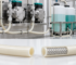 Industrial processing setup with cream-colored hoses connected to stainless pumps and tanks in a clean manufacturing environment