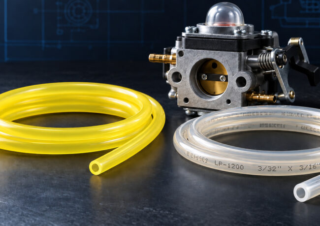 Carburetor with yellow and clear fuel hoses on a dark workshop table surface.