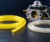 Carburetor with yellow and clear fuel hoses on a dark workshop table surface.